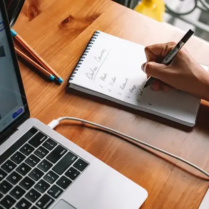 Writing notes beside a laptop